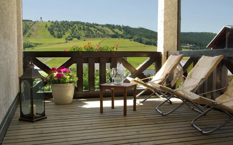 Balkon mit Liegestühlen und Blick auf Skihang und Wald
