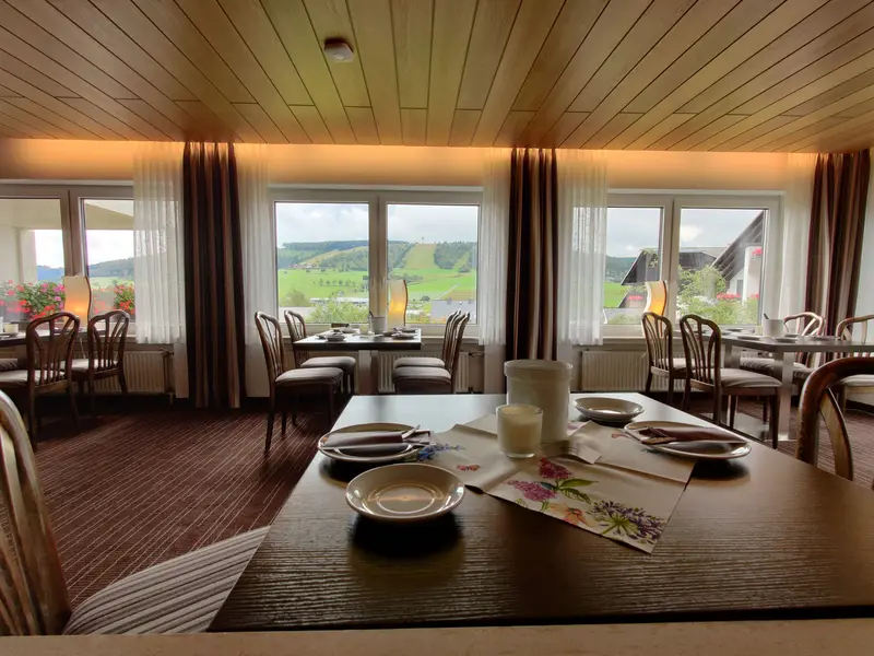 Frühstücksraum mit großen Fenstern und Blick ins Grüne