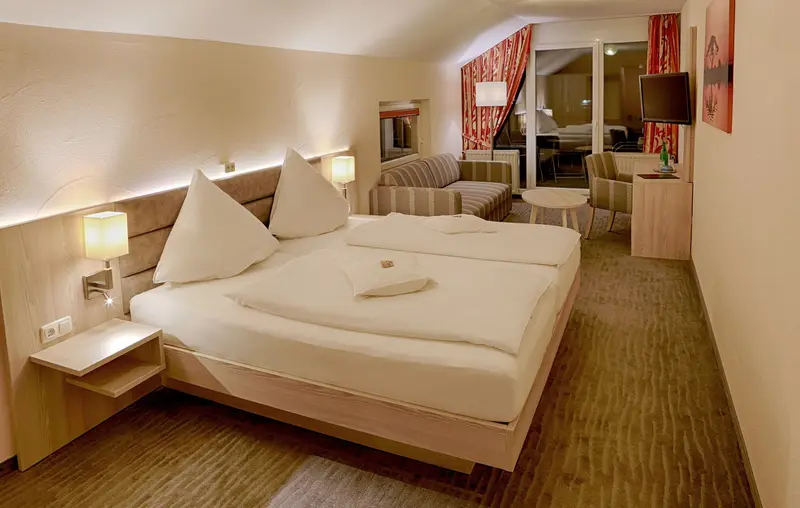Doppelzimmer mit hellem Holzbett und Sitzecke