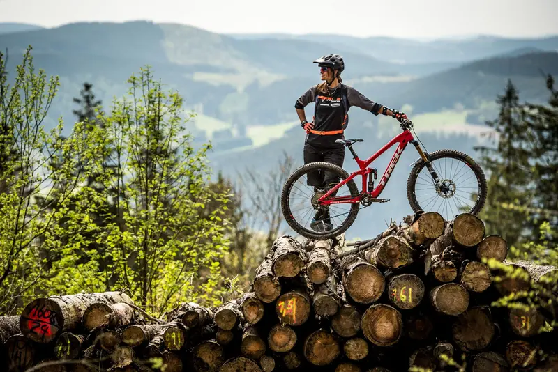 Mountainbikerin auf einem Holzstapel über dem grünen Tal